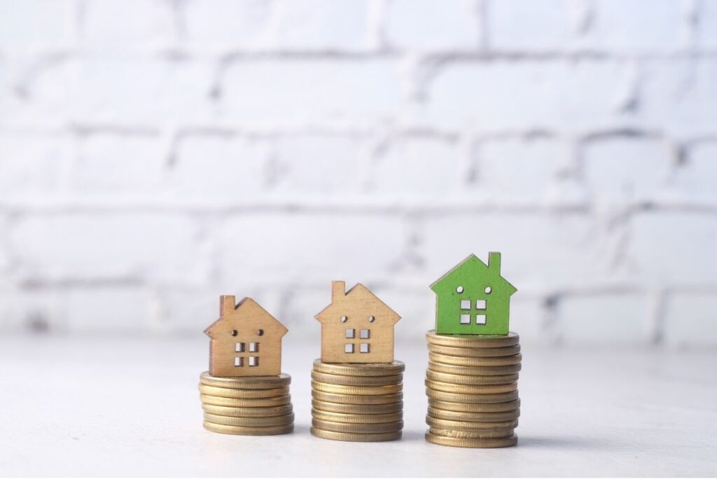 The concept of finance stack of coins and houses on top on table