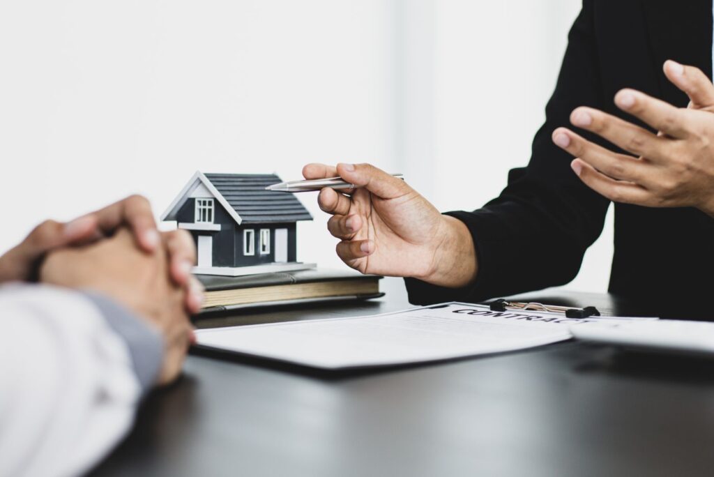 Hands discussing property contract over paperwork