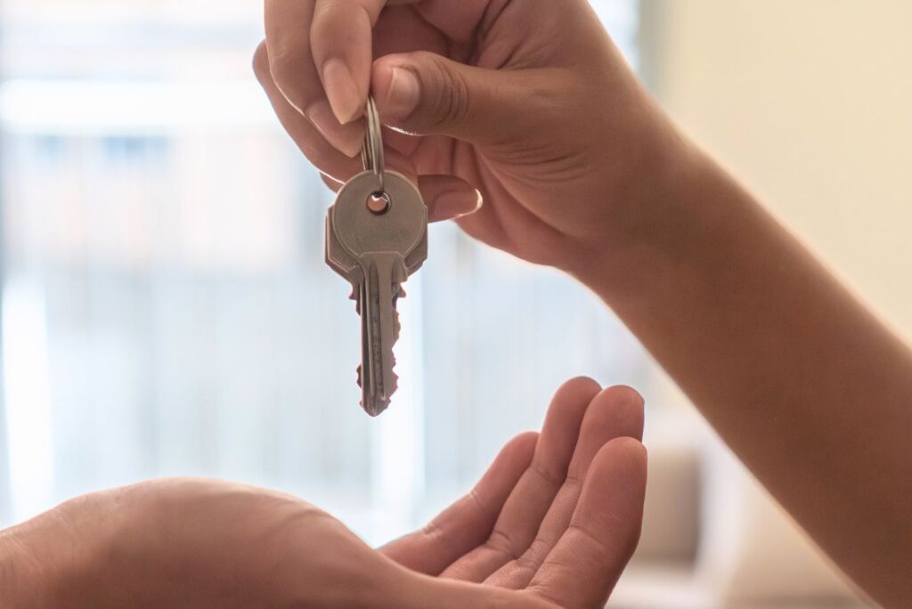 Hands exchanging home keys representing new ownership moving
